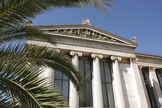 GREECE, Athens, Angled view of the National Academy columned facade partially obscured by palm
