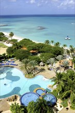 WEST INDIES, Dutch Antilles, Aruba, View over beach side hotel pool with clear blue sea beyond