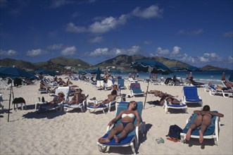WEST INDIES, French Antilles, St Martin, Orient beach with people sunbathing on loungers