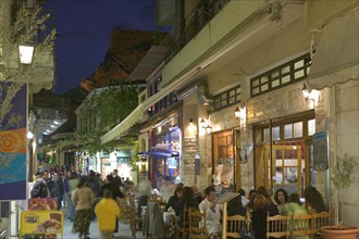 GREECE, Athens, Street cafes in Plaka at dusk with the Acropolis in the background.