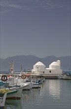GREECE, Saronic Islands, Aegina, Fishing boats moored in Aegina Town next to a small white church