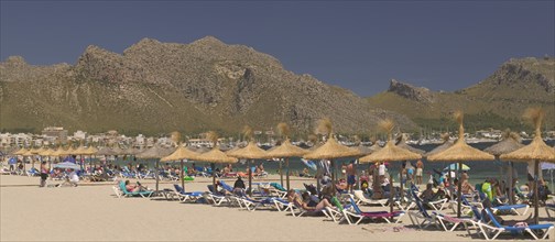 SPAIN, Balearic Islands, Majorca, "Sun loungers, tourists and parasols on the beach at Puerto de