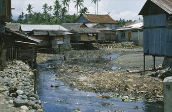 INDONESIA, Sulawesi, Wani.,  Housing next to a river contaminated with rubbish
