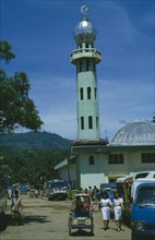 INDONESIA, Toraja, Rantepao Mosque. View down street with cars and people towards green Mosque.