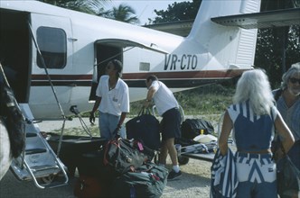 WEST INDIES, Cayman Islands, Little Cayman, Passenger plane with tourists on runway unpacking