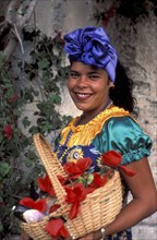 CUBA, Havana, Woman in traditional dress holding a flower basket