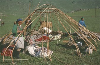 CHINA, Xinjiang, Altai Region, "Kazakh nomads building kigizuy, erecting circular frame."