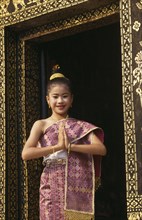 LAOS, Luang Prabang, Young girl dressed for New Year festivities framed in doorway of temple.