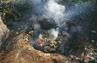 LIBYA, Cyranaica, Cooking meat on hot stones in a hole in the ground.