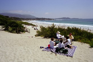 USA, California, Carmel, Carmel Beach with people on blanket among sand dunes in the foreground