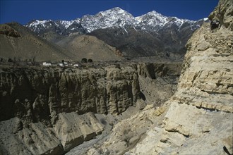 NEPAL, Mustang, Mountain pass and steep sided gorge with snow capped mountain peaks in the distance