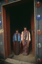 BHUTAN, Paro Valley, Heyphu, Two girls framed by doorway of monastery.