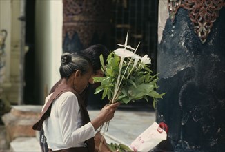 MYANMAR, People, Woman making offering of flowers.