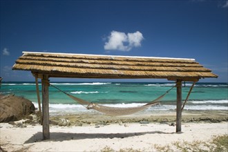 WEST INDIES, St Vincent & The Grenadines, Palm Island, Hammock under a shelter by the beach at Palm