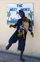 WEST INDIES, St Vincent & The Grenadines, Union Island, Man dancing beside a restaurant sign in