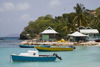 WEST INDIES, St Vincent & The Grenadines, Mustique, Fishing boats and beachside houses in Britannia