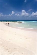 WEST INDIES, Barbados, Christ Church, Couple walking towards sea defences on Rockley Beach also