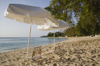 WEST INDIES, Barbados, St Peter, Sunshade umbrellas on Gibbes Bay beach in late afternoon
