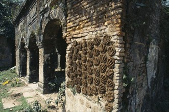 BANGLADESH, Dinajpur, Drying cakes of cow dung on wall of old building for use as fuel.