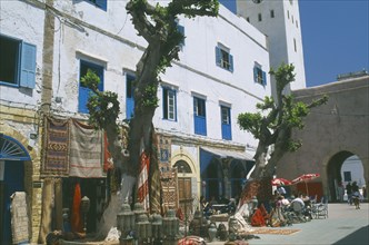 MOROCCO, Essaouira, Square with white painted buildings with blue shutters.  Shop with display of