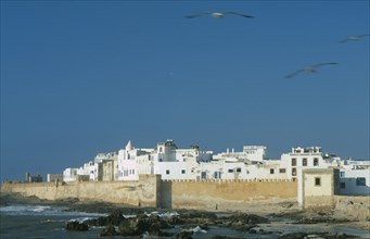 MOROCCO, Essaouira, Fortified coastal town with waves breaking against rocks in the foreground.