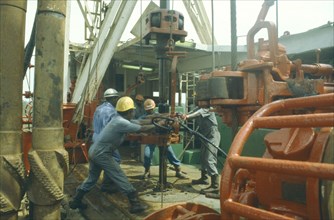 NIGERIA, Rivers State, Workers using drill on oil rig.