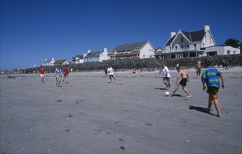 UNITED KINGDOM, Channel Islands, Guernsey, Castel. Cobo Bay. Young men playing football on sandy