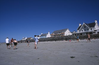 UNITED KINGDOM, Channel Islands, Guernsey, Castel. Cobo Bay. Young men playing football on sandy