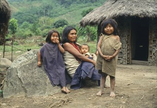 COLOMBIA, People, Kogi, Kogi woman sitting on the ground with three children outside their thatched