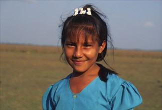 COLOMBIA, Casanare, A young Llanera girl wearing a blue top and a hair clip with dogs on.