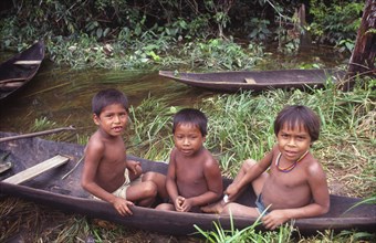 COLOMBIA, Vaupes, Three tukano Indian boys sat in canoe and empty canoe behind them.