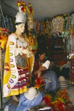 BOLIVIA, La Paz, "Costume maker for Oruro Carnival. Woman sat, holding large spool of thread."
