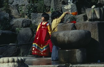 SOUTH KOREA, Children, Children wearing traditional dress drinking from well.