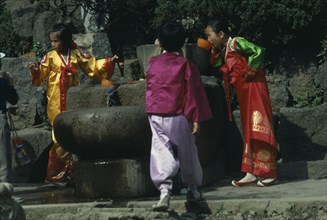 SOUTH KOREA, People, Children wearing traditional national dress drinking from well.