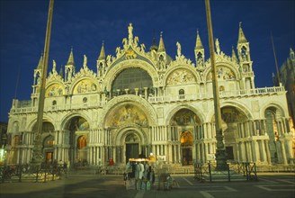 ITALY, Veneto, Venice, Basilica di San Marco exterior facade at night with clothing stall in square
