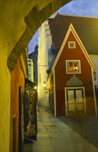 ESTONIA, Tallinn, Old Town street at night. lit by lanterns in wall brackets.