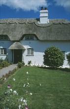 ENGLAND, Hampshire, Lyndhurst, Thatched Cottage seen from across green front lawn.