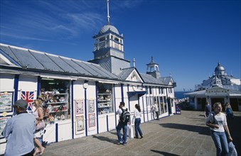 ENGLAND, East Sussex, Eastbourne, Pier gift shops with visitors walking past.