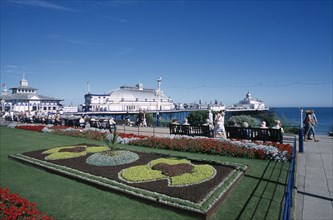 ENGLAND, East Sussex, Eastbourne, Seafront promenade formal flowerbed display with pier behind.