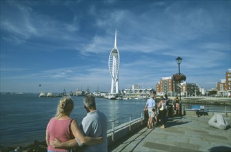 ENGLAND, Hampshire, Portsmouth, Spice Island. A couple arm in arm looking towards the Spinnaker