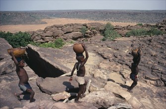 MALI, Water, Dogon children carrying water in pots and calabashes on their heads.