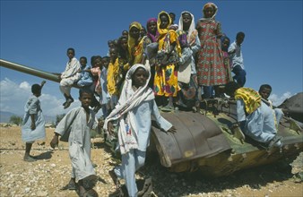 ERITREA, Children, Children playing on rusting tank on road between Asmara and Keren near Aderde.