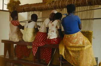 RWANDA, Nyundo, Young women weaving at hand loom.
