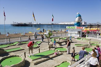 ENGLAND, East Sussex, Brighton, Tourist family playing crazy golf on the seafront with Brighton