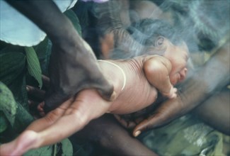 SUDAN, People, Rituals, Azande tribe birth ritual where new baby is passed through medicinal smoke.