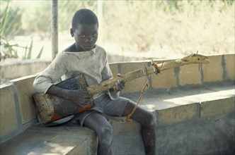 ZAMBIA, Chingola, Boy with guitar made from oil can and piece of wood.