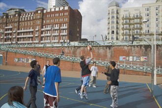 ENGLAND, East Sussex, Brighton, Young men playing Basketball on the lower esplanade. Seafront Hotel