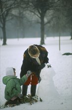 ENGLAND, London, Woman and child building a snowman in heavy snow in Hyde Park.