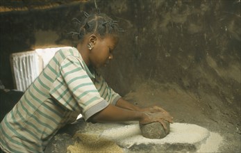 BURKINA  FASO, Bisaland, Sigue Voisin, Near Garango.Young girl grinding grain.