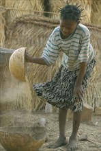 BURKINA  FASO, Bisaland, Sigue Voisin, Near Garango. Young girl winnowing.